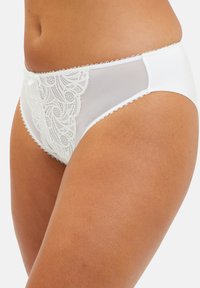 Culotte blanche taille haute avec des panneaux en dentelle et des côtés en maille transparente. Présente un délicat empiècement sur les bords et un petit nœud décoratif à l'avant.