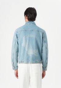 Hele sinine denim-jakk, mille seljal on tuhm graafika. Omab nööbid ees, kaht rinnataskut ja reguleeritavaid mansette.