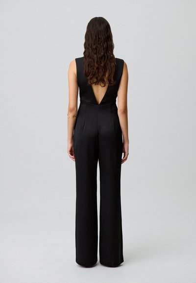 Mono negro con diseño de espalda en V, patas anchas y sin mangas. Tela suave con un corsé ajustado y una silueta relajada.