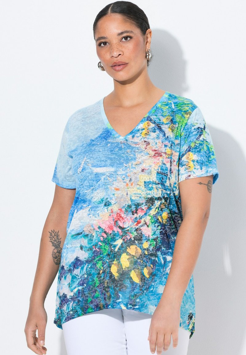 Jasnoniebieska koszulka z dekoltem w serek, zdobiona kolorowym abstrakcyjnym wzorem z elementami kwiatowymi w odcieniach żółtego, różowego i zielonego. Krótkie rękawy i luźny krój.
