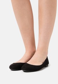 Ballerine in suede nero con punta arrotondata e suola piatta. Caratterizzate da una texture liscia e un design minimalista, adatte per un abbigliamento casual.