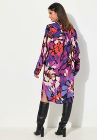 D�ługa, zwiewna sukienka w kwiatowy wzór w odcieniach różu, purpury i pomarańczu. Wykonana z lekkiego materiału, z długimi rękawami i bocznymi rozporkami.