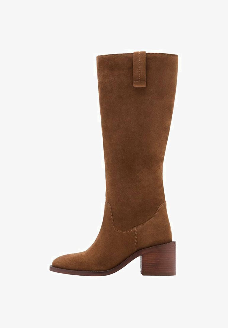 Bota de ante marrón de caña alta con puntera cuadrada y tacón de madera apilada. Presenta una etiqueta en forma de lazo en la parte superior para facilitar su colocación.