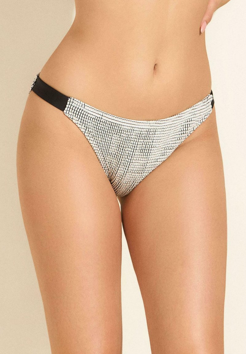Majtki w stylu bikini w czarno-białym wzorze, z teksturowanej tkaniny, niskim kroju i cienkimi czarnymi bocznymi paskami.