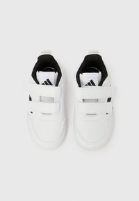 Biele športové topánky s čiernymi prvkami, vyrobené zo syntetického materiálu, so dvoma páskami na suchý zips a vnútornou sieťovinovou podšívkou.