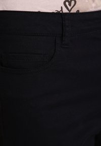 Svarta denimjeans med en standardficka, rena sömmar och en slät yta. Midjebandet sitter något ovanför höfterna.