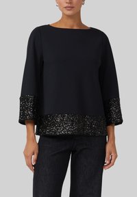 Schwarzes Top mit dreiviertellangen Ärmeln und einem glänzenden, glitzernden schwarzen Paillettenabschluss. Hergestellt aus glattem Stoff, mit gerader Silhouette.