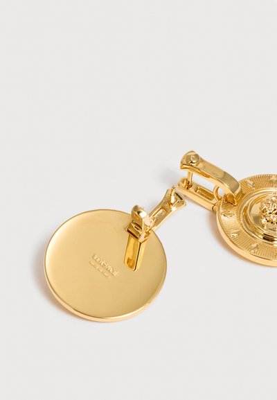 Χρυσό σκουλαρίκι Versace με κλιπ, διακοσμημένο με μετάλλιο με κεφάλι λιονταριού και γυαλισμένη κυκλική πίσω πλάκα με χαραγμένο το όνομα της μάρκας.