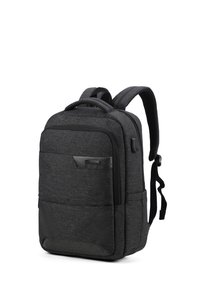 Zaino in tessuto nero con più scomparti, spalline imbottite, superficie texture e una piccola tasca frontale. Le chiusure con zip sono evidenti.