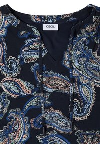 Tissu bleu marine avec motif paisley pastel dans des tons de bleu, rose et vert, avec un col rond et une étiquette blanche indiquant "CECIL."