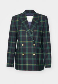 Blazer croisé en tissu foncé avec un motif à carreaux verts et jaunes. Doté de boutons dorés et de deux poches horizontales.