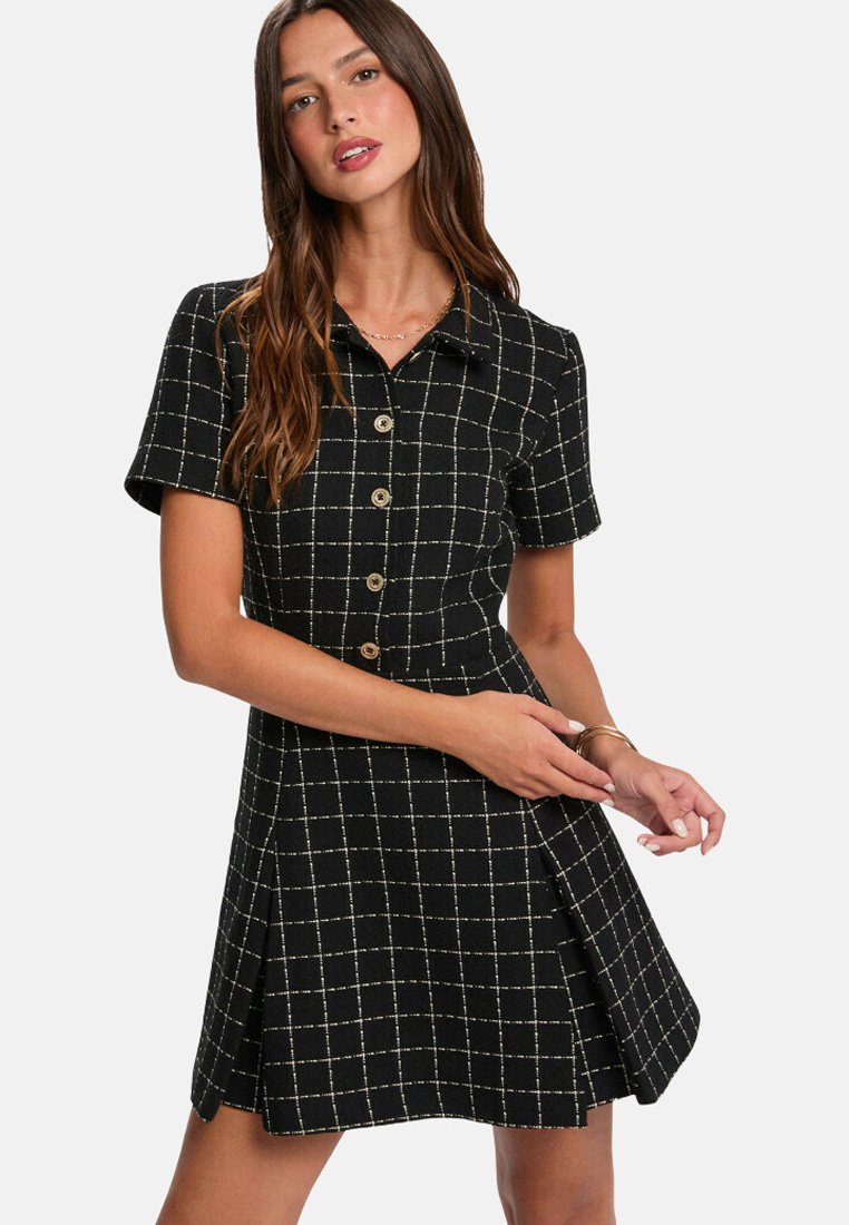 Robe noire à manches courtes, avec un col et un motif à carreaux dorés. Comprend des boutons sur le devant et une jupe évasée. Texture de tissu lisse.