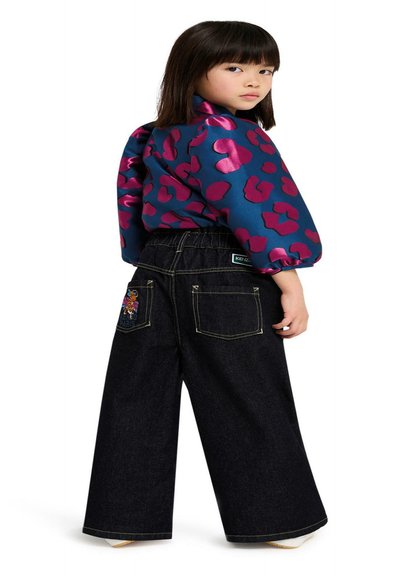 Blauwe en paarse panterprint satijnen top met pofmouwen, gecombineerd met donker denim wijde broek met geborduurde achterzakken.