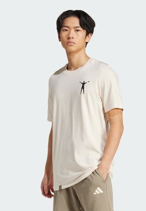 T-shirt in cotone color crema con maniche corte, caratterizzato da una grafica silhouette nera sul lato sinistro del petto e una vestibilità comoda.