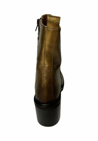 Botín de cuero marrón hasta el tobillo con puntera redonda, acabado suave, cremallera trasera y un tacón grueso negro. Presenta detalles de costura mínimos.