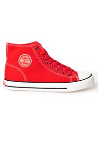 Sneaker alta in tela rossa con punta e suola in gomma bianca. Presenta strisce nere sulla suola e una patch rotonda con logo sul lato.