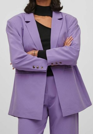 Purple blazer made of smooth fabric, featuring a tailored design with lapels, front pockets, and buttoned cuffs. Worn over a black top.