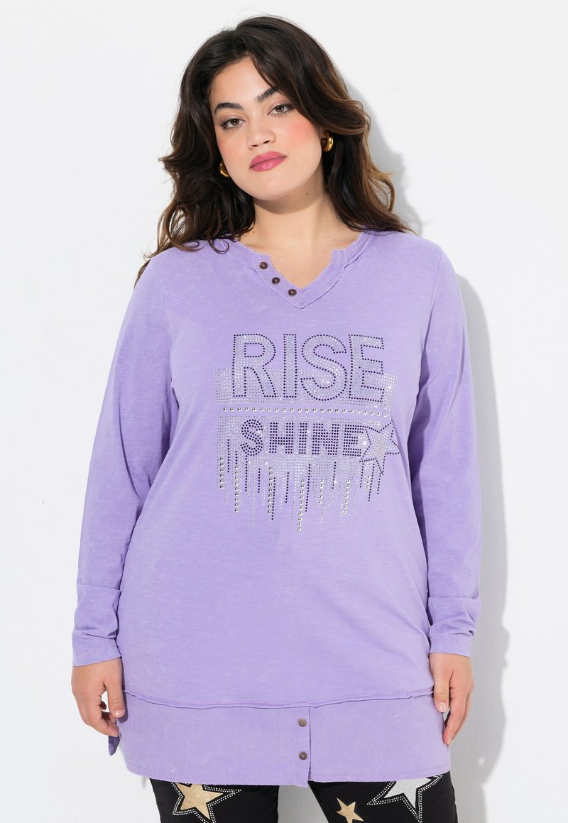 Maglietta a maniche lunghe, dal taglio morbido, di colore lavanda con scollatura a V e tre bottoni decorativi. Presenta una grafica luccicante "RISE SHINE" arricchita da accenti di stelle.