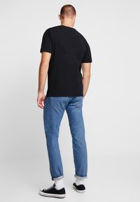 Sort bomulds T-shirt med rund hals, parret med lyseblå denimjeans og sorte sneakers. Fokuser på pasform og enkelt design.