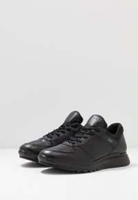 Czarne skórzane sneakersy o eleganckim fasonie, wyposażone w gładką teksturę, sznurowane zapięcie, wyściełany kołnierz oraz kontrastowe akcenty.