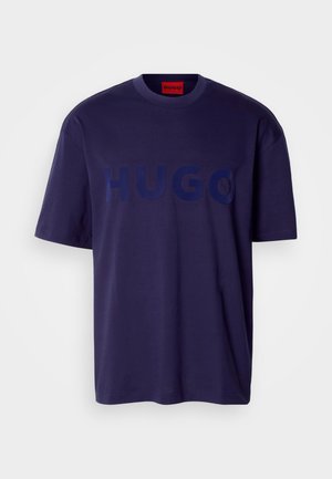 Navyblauwe katoenen t-shirt met een groot ton-sur-ton "HUGO" logo aan de voorkant, korte mouwen en een ronde hals. Eenvoudig ontwerp met een ontspannen pasvorm.