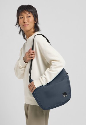 Borsa a messaggero navy realizzata in tessuto resistente, dotata di una patta pieghevole, tracolla regolabile e una patch con logo sulla parte anteriore.