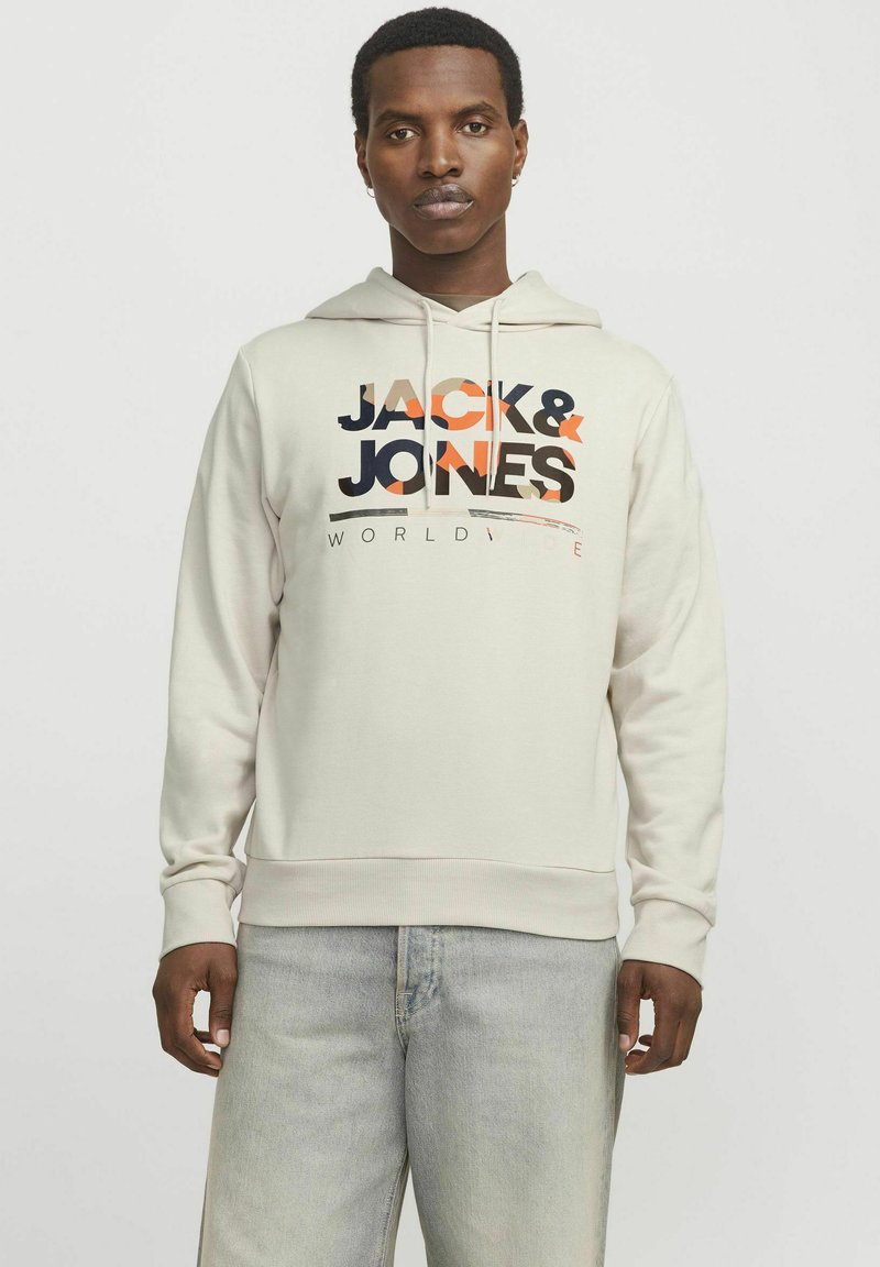 Sudadera crema hecha de tela suave; presenta un gráfico central con "JACK & JONES" en negro y naranja. Capucha ajustable y puños de canalé.