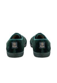 Zöld bársony cipők sötét gumitalppal és texturált felülettel. A sarkon egy kis logó címke található, amely környezetbarát dizájnnal büszkélkedik.