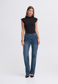 Body noir côtelé avec manches courtes, associé à un jean droit bleu moyen et des talons noirs à bout pointu. Design épuré et ajusté.