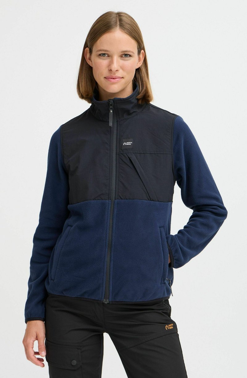 Veste polaire isolante navy avec un panneau noir sur le haut du devant, poches zippées, col montant et tissu texturé.