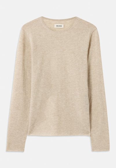Beige pitkähihaine paita, joka on valmistettu pehmeästä kankaasta. Paita on pyöreäkauluksinen ja sen vasemmassa alareunassa on hienovarainen ommelkoristelu.