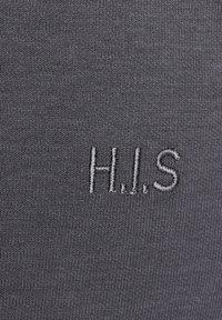 Grau stoff mit feiner gerippter textur, versehen mit gestickten buchstaben "H.I.S." in einem etwas helleren grau, auffällig platziert.