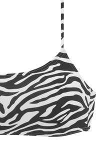 Melnā un baltā zebras raksta bikini topiņš ar plānām regulējamām siksniņām, ar gludu auduma tekstūru un kvadrātveida dekoltē dizainu.