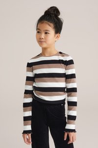 Svītrots garo piedurkņu krekls melnā, baltā un brūnā krāsā. Rievota tekstūra ar apaļu kaklu un viļņotām aprocēm. Apvienots ar melnajām kordūru biksēm.