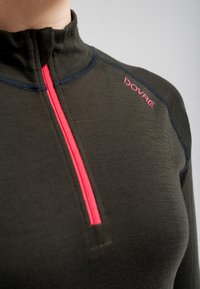 Mørkegrøn pullover med høj hals, har en lys pink lynlås og sy-accenter. Brandlogo i pink på skulderen. Blød tekstur.