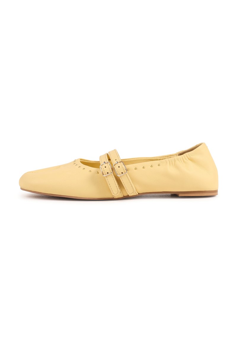 Chaussure plate jaune avec bout arrondi, brides à double boucle, petits clous près de l'ouverture et talon arrière élastiqué.