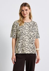 Krótki rękaw top w kremowym kolorze z czarnym abstrakcyjnym wzorem, z okrągłym dekoltem i luźnym krojem, wykonany z miękkiego materiału.