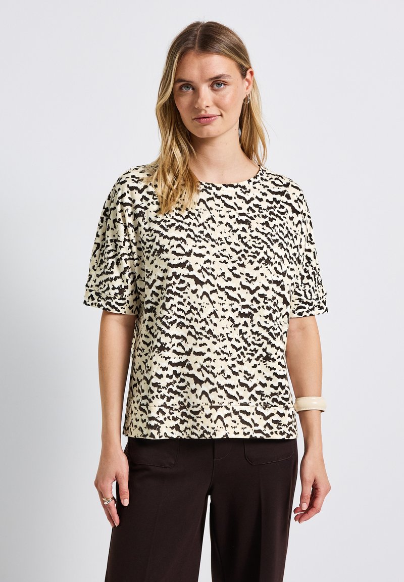 Krótki rękaw top w kremowym kolorze z czarnym abstrakcyjnym wzorem, z okrągłym dekoltem i luźnym krojem, wykonany z miękkiego materiału.