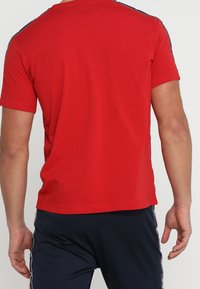 Camiseta roja de manga corta, hecha de algodón, con un escote redondo y un diseño liso sin logotipos ni patrones visibles.