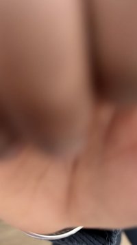 Gros plan d'une main avec les doigts partiellement visibles, tenue au-dessus d'une surface en tissu sombre avec une petite étiquette blanche.