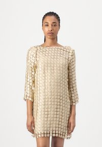 Guldig blommig spetsklänning med trekvartslånga ärmar, fyrkantig halsringning och ett intrikat mönster. Tyget har en genomskinlig textur med lagerdetaljer.