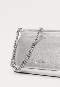 Silver metallic clutch bag with a textured finish and a silver chain strap. Features a fold-over design, visible logo detail.