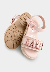 Różowe sandały z fakturowanym paskiem z napisem "BAKE", regulowanym zapięciem na kostkę oraz podeszwą typu espadryle z juty.