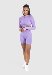 Set atletico viola composto da un top cropped con zip e maniche lunghe e pantaloni corti a vita alta coordinati, realizzati in tessuto dalla texture morbida.