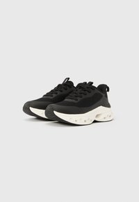 Μαύρα αθλητικά παπούτσια με λείο άνω μέρος με διακοσμητικά στοιχεία από δίχτυ, λευκή ενδιάμεση σόλα με λεπτομέρειες αερόσουστας και υφασμένη εξωτερική σόλα από καουτσούκ.