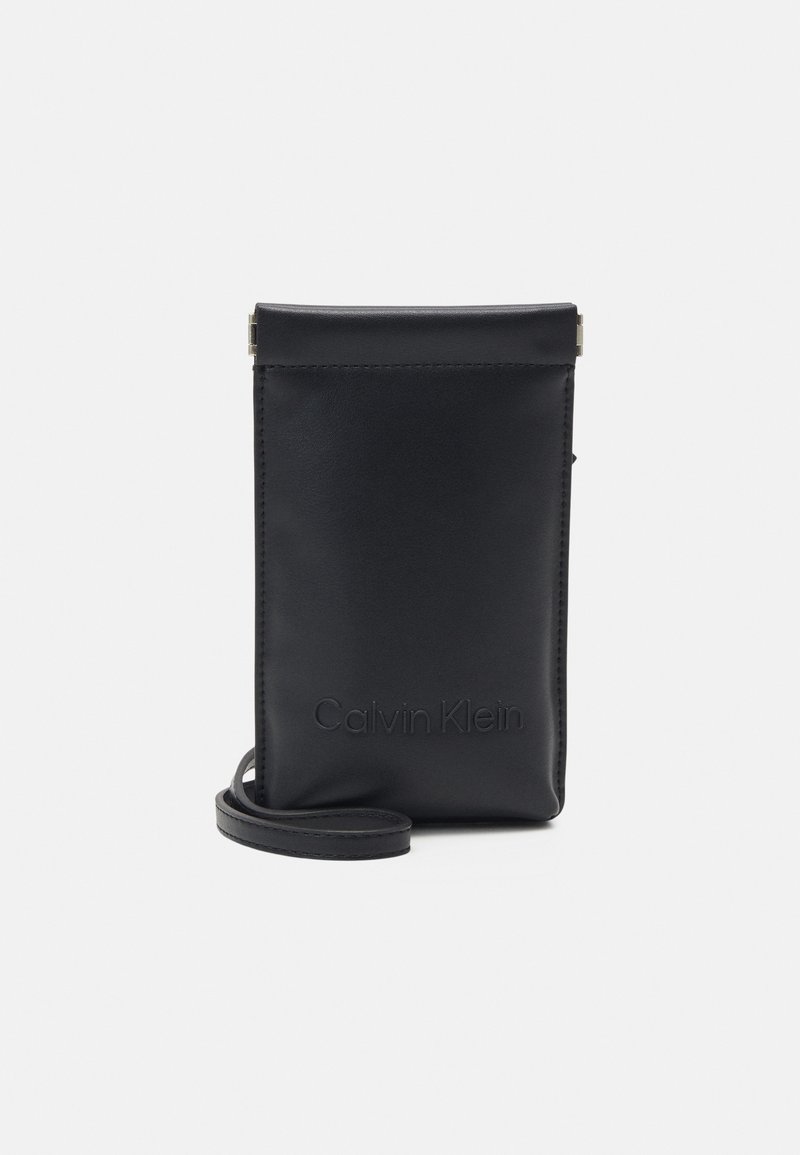 Funda para teléfono de cuero negro con un acabado suave, que cuenta con el logo de Calvin Klein en relieve, cierre superior y correa de hombro desmontable.