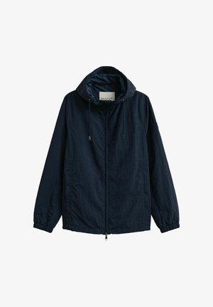 Giacca leggera blu navy con cappuccio, cerniera frontale, polsini elastici, coulisse e tasche laterali, distesa su uno sfondo bianco.