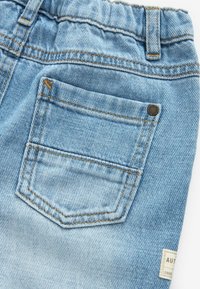 Shorts in denim azzurro chiaro con una tasca posteriore caratterizzata da cuciture a contrasto, un'etichetta con testo e una leggera texture sfumata.