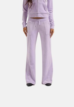 Vrouw draagt lichtpaarse sweatpants met wijde pijpen, voorzakken en een taille met koordje, gecombineerd met een cropped hoodie met rits.