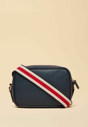 Tumesinist rist-keha nahast ristkott, millel on lai kangast rihm, millel on beežil taustal punased ja valged triibud.